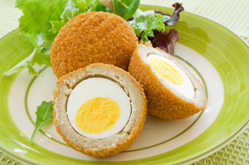 Scotch eggs on a plate with a green salad